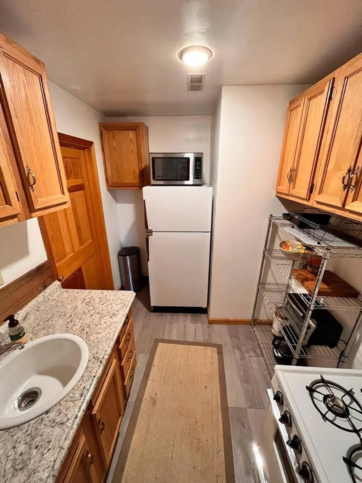 Close-up view of the kitchen with a granite countertop, wooden cabinets, stainless steel appliances, and a gas stove. The countertop is spacious, ideal for meal preparation or casual dining.