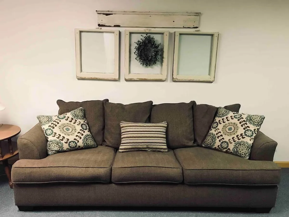 A comfortable sofa with decorative pillows and wall decor, set in a well-lit corner of the living room. The scene evokes relaxation and offers a spot for quiet reading, coffee, or casual conversation, enhanced by soft, natural light.