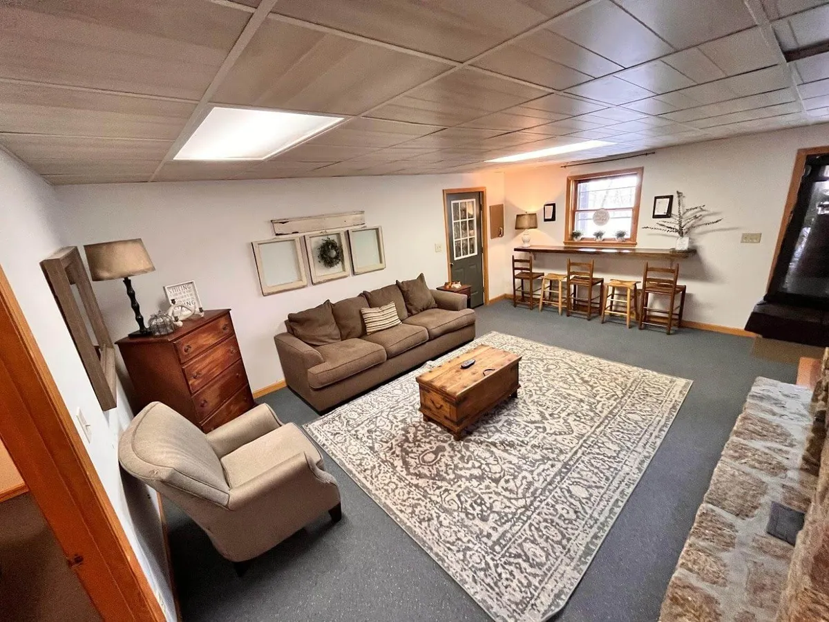 A cozy living area with a sofa, coffee table, and rug, accompanied by decorative items and a small bar area. The setup encourages socializing, relaxing, and group activities such as game nights or movie watching, aligning with the section’s emphasis on togetherness.
